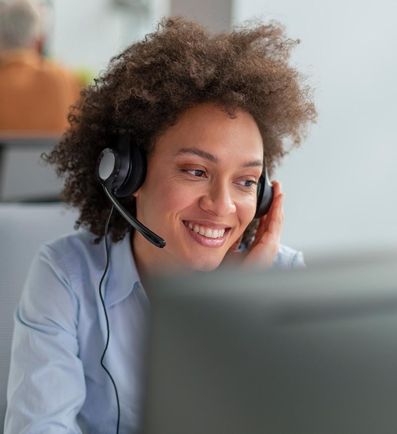 Woman wearing headset sitting in front of computer.